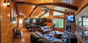 A log cabin interior with a dining area, kitchen, and living room with a fireplace.