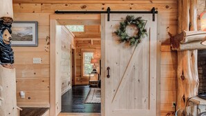 A wooden interior with a sliding door, a fireplace, and a framed picture on the wall. - Big Sky Lodge 5 Br + Bonus-4 Ensuites, Mt Views, hot tub, game room,Pet friendly (McDowell County)