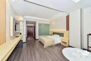 A modern hotel room with a bed, bedside table, TV, and a bathroom with a bathtub and sink.