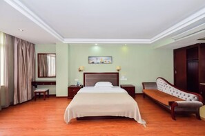Een hotelkamer met een bed, nachtkastjes, een bankje, een bureau en een kledingkast.