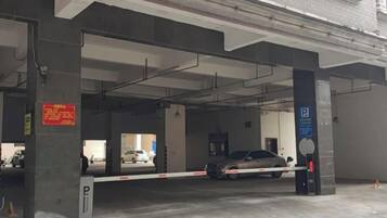 Een parkeergarage met betonnen pilaren, een hekwerk en een blauw parkeersbord.