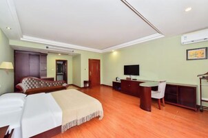 Una habitación de hotel con cama, escritorio, televisor y armario.