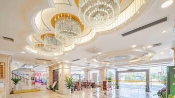 A spacious lobby with a grand chandelier, a staircase, and a seating area.