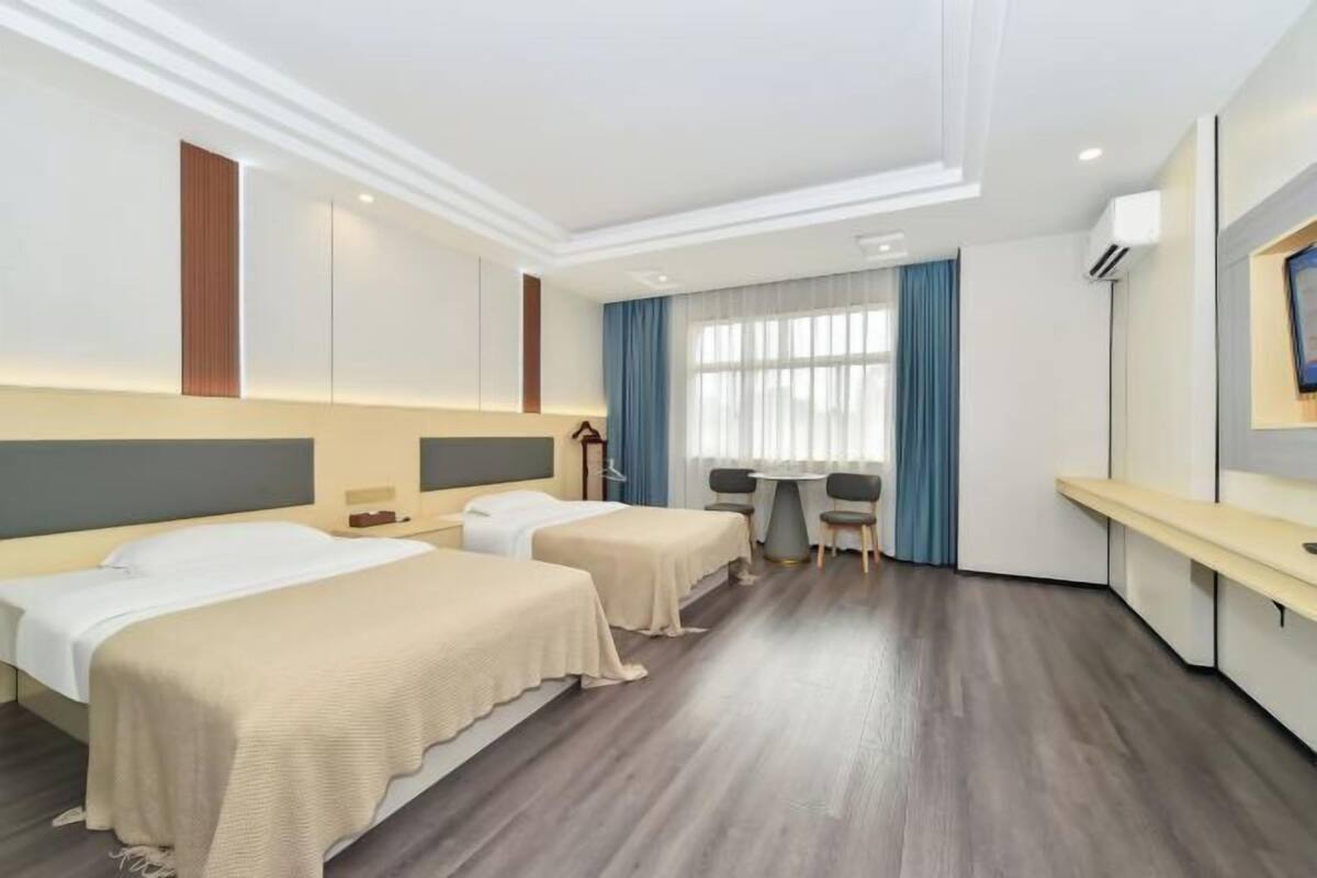 Quarto de hotel com duas camas, uma escrivaninha e uma cadeira.