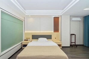 A hotel room with a bed, bedside tables, a nightstand, a wardrobe, a mirror, and an air conditioning unit. - Dong He Hotel (Dongxing)