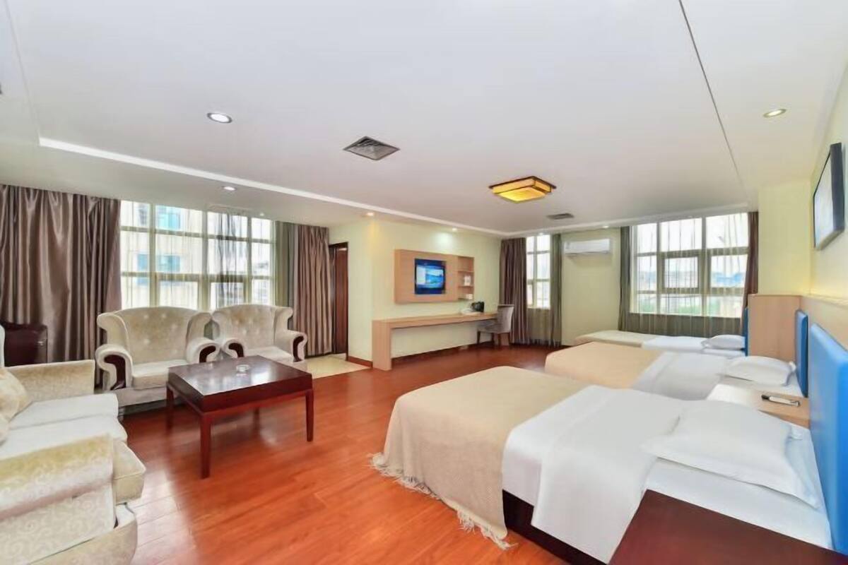 Quarto de hotel com sofás, uma cama, escrivaninha e televisão.