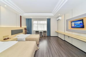 Habitación de hotel con dos camas, televisión, escritorio y ventana con cortinas.
