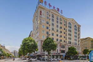 Een hotel met meerdere verdiepingen, met een klassiek ontwerp, grote ramen en een opvallende ingang.