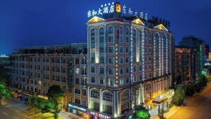 Un hotel de varios pisos con un cartel llamativo en la parte superior, grandes ventanales y una fachada bien iluminada.