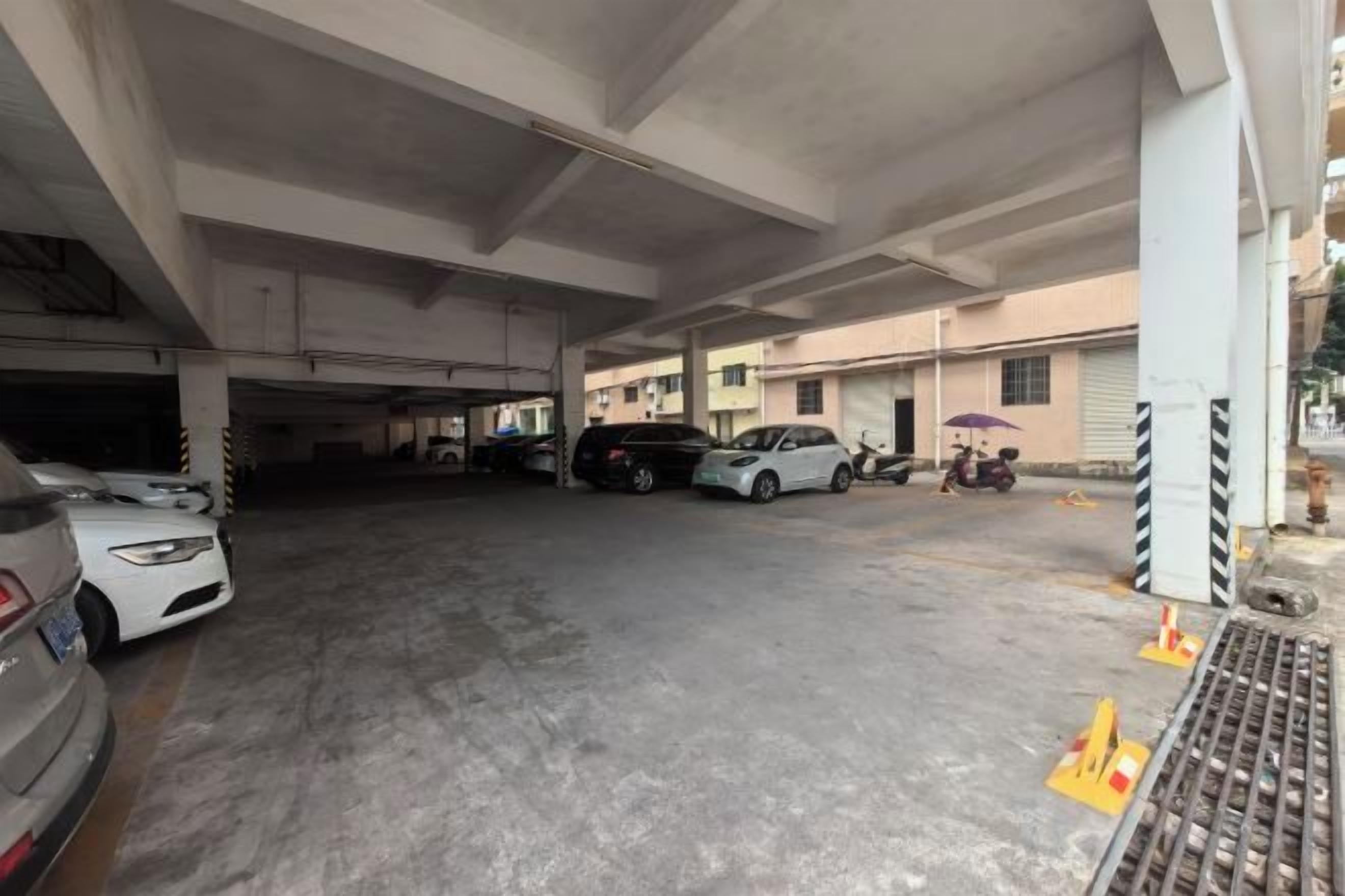 An underground parking area with multiple cars parked, concrete pillars, and a pedestrian walkway.