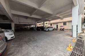 An underground parking area with multiple cars parked, concrete pillars, and a pedestrian walkway. - Dong He Hotel (Dongxing)
