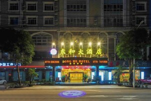 Un hotel con una entrada destacada, señalización iluminada y fachada bien iluminada.