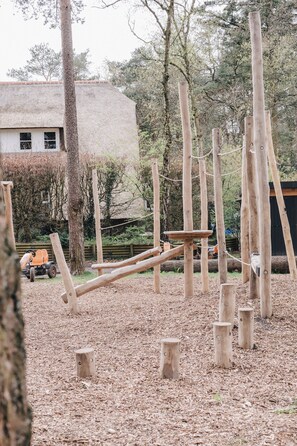 Explore the elevated play structure amidst the woods, featuring multiple levels and wooden posts.