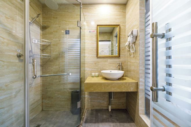 A modern bathroom with a glass-enclosed shower, a beige vanity with a sink, and a mirror above the vanity.