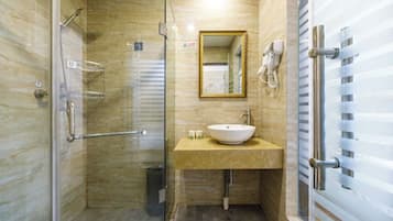 A modern bathroom with a glass-enclosed shower, a beige vanity with a sink, and a mirror above the vanity.