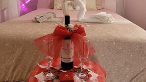 Un dormitorio con una cama, una mesa con una botella y vasos, y un atrapasueños.