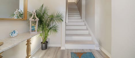Una escalera con peldaños blancos y barandilla, que conduce a una puerta en la parte superior.