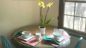 A dining area with a round table, chairs, a potted orchid, and a framed picture on the wall.