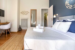 A modern hotel room with a large bed, a desk, and a chair.