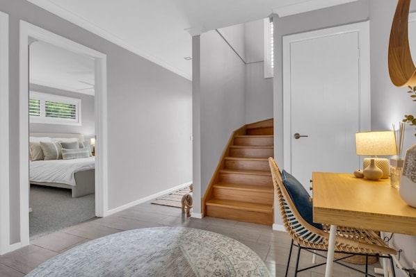 A modern interior with a staircase leading to a bedroom, a dining area with a table and chairs, and a round rug on the floor.