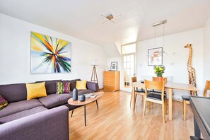A modern living room with a sofa, coffee table, and a dining area with a table and chairs.