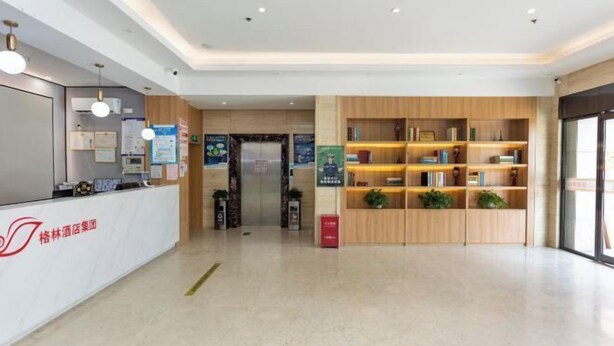 Un espace d’accueil d’hôtel comprenant un comptoir de réception, une bibliothèque en bois et une vue dégagée sur l’ascenseur.