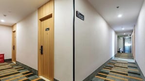 Un couloir d’hôtel avec un comptoir d’enregistrement, une porte en bois et un sol recouvert de moquette.