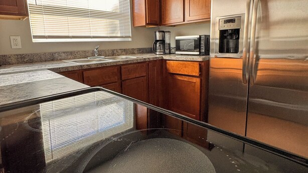 A kitchen with wooden cabinets, a stainless steel refrigerator, a microwave, and a coffee maker.