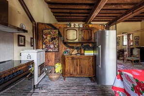 Una cocina rústica con armarios de madera, un refrigerador de acero inoxidable y un salpicadero de azulejos.
