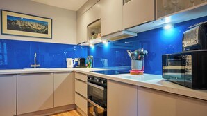 Eine moderne Küche mit weißen Schränken, einer blauen Spritzschutzwand und Edelstahlgeräten.