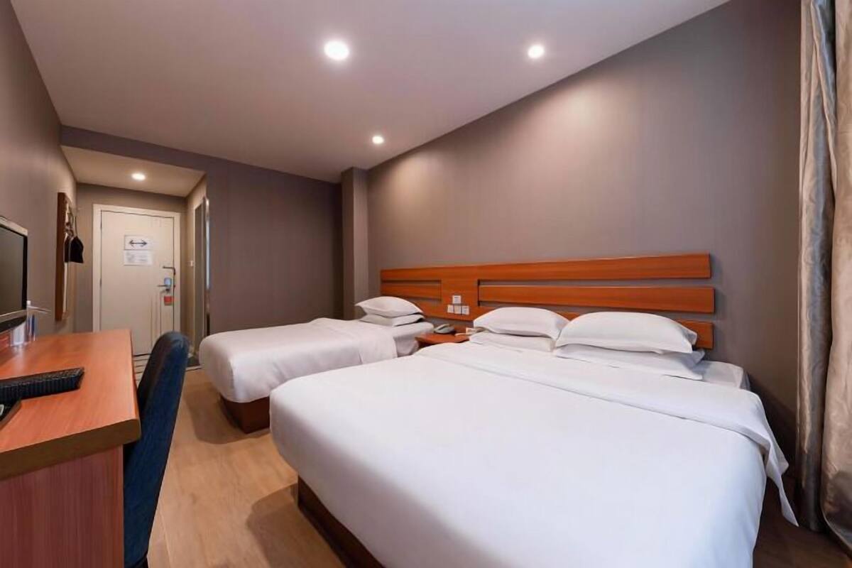 A hotel room with two single beds, a desk with a chair, a television, and a door with a sign.