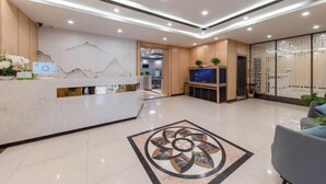 Una moderna zona de recepción con mostrador de mármol, un diseño decorativo en el suelo y un mostrador de recepción con un monitor de computadora.