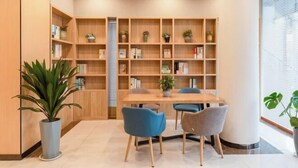 Una biblioteca moderna con una estantería de madera, una mesa redonda y dos sillas.