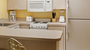 Cocina compacta con microondas, estufa, tostadora y refrigerador.