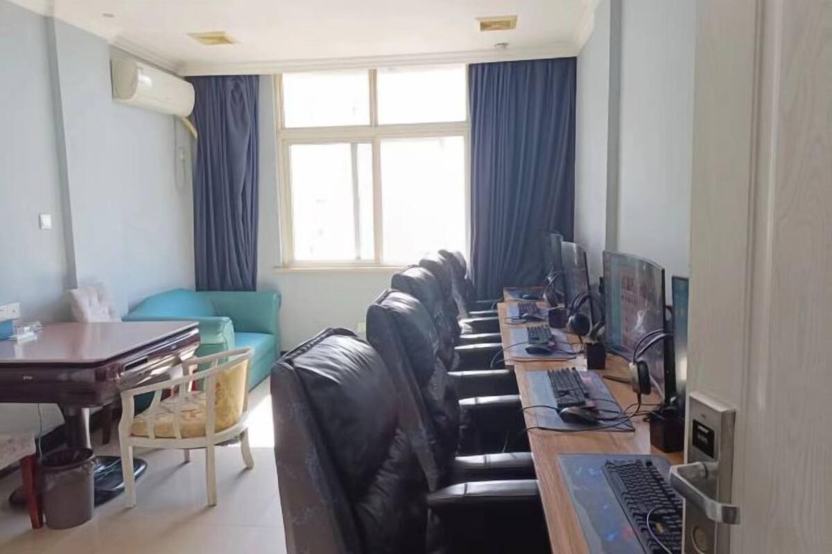 Une pièce avec une longue table, des chaises en cuir noir, un ordinateur et une fenêtre avec des rideaux.