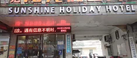 The entrance to Sunshine Holiday Hotel with a glass door and signage in both English and Chinese.