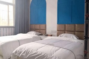 Una habitación de hotel con dos camas, una ventana con cortinas y una pared de acento azul.