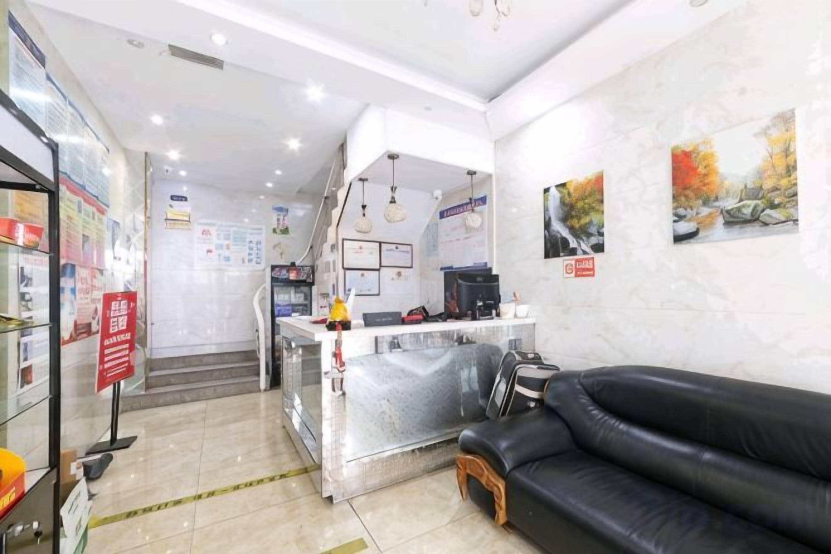 A reception area with a counter, a black leather sofa, and a staircase leading to the upper floor.