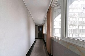 A narrow hallway with a window on the right, a door at the end, and a sign on the wall. - Wuwei E-sports Sunshine Holiday Hotel (Wuwei)