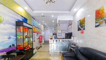 A hotel lobby with a reception desk, seating area, and a wall with a mural.