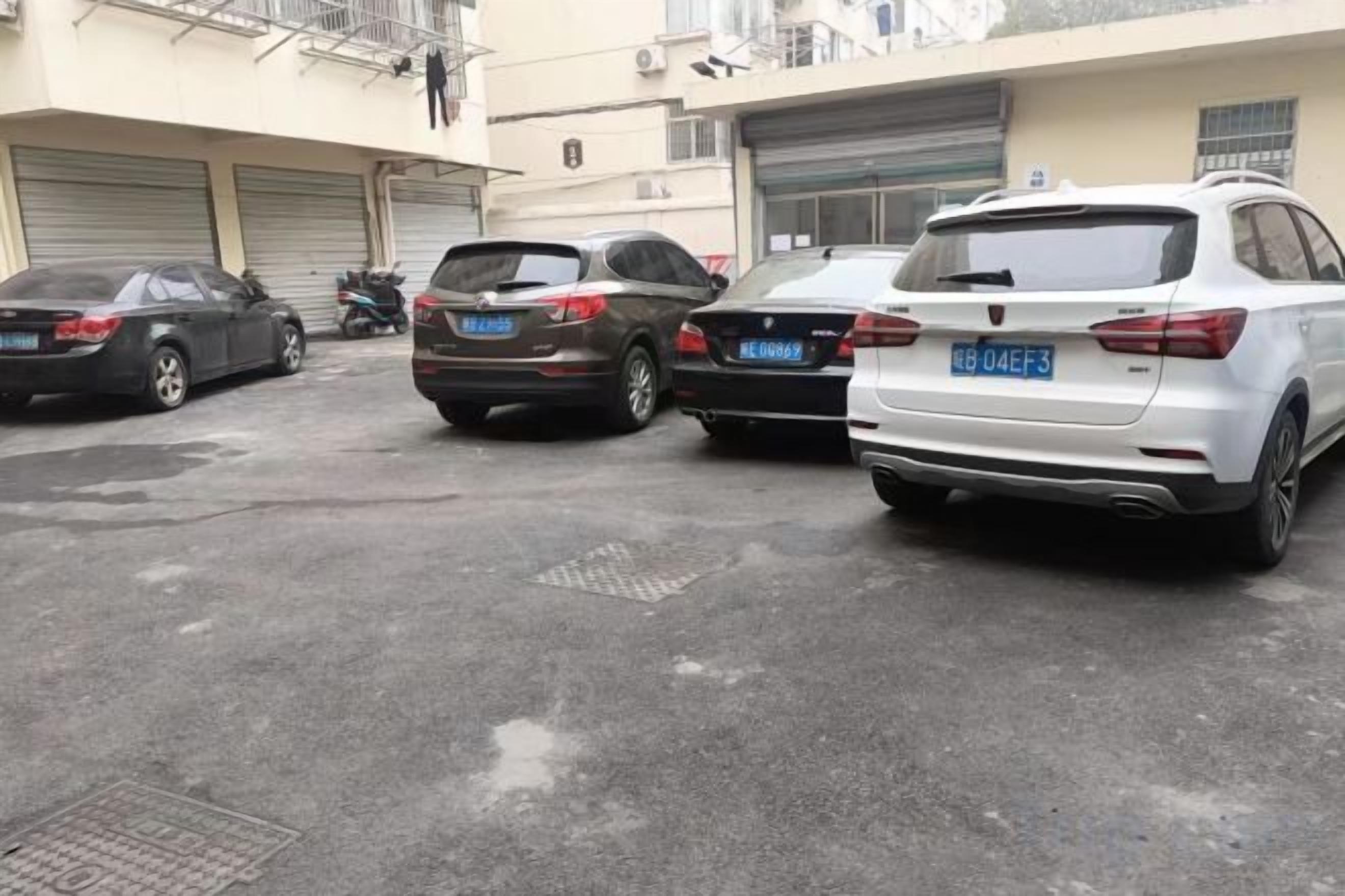 A parking lot with several cars parked, including a white sedan and a black SUV.
