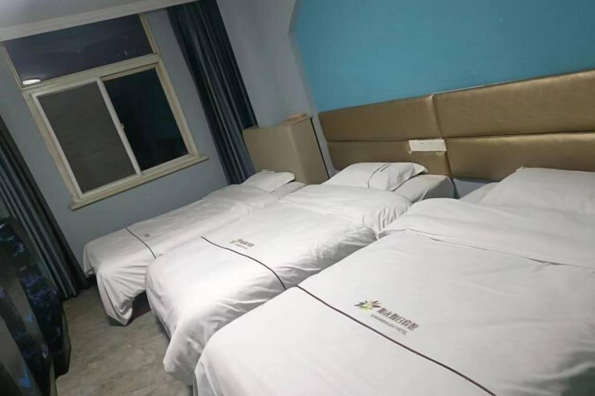Une chambre d’hôtel avec deux lits, une fenêtre et un mur bleu.