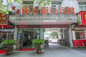 The entrance to Sunshine Holiday Hotel with a red carpet, potted plants, and a signboard. - Wuwei E-sports Sunshine Holiday Hotel (Wuwei)