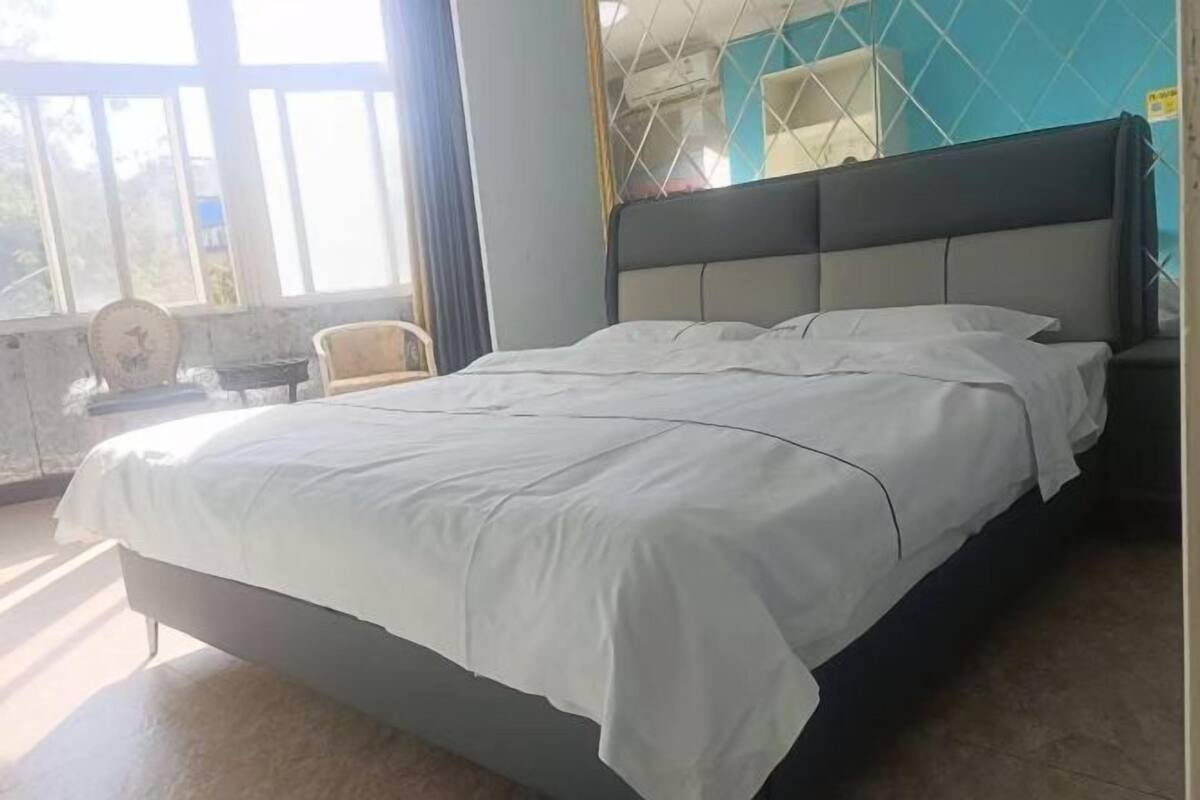 Un lit avec une couvre-lit blanche, une tête de lit et une table de chevet avec une lampe.