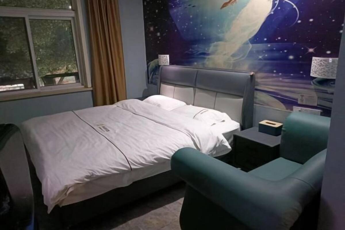 Une chambre à coucher avec un lit, une table de chevet, une lampe, une fenêtre et une fresque murale.