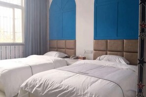 Une chambre d’hôtel avec deux lits, une fenêtre et un mur bleu.
