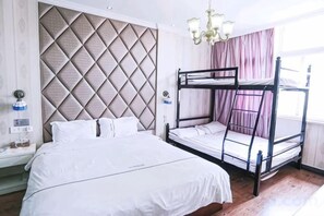 A hotel room with a bunk bed, a large bed, a headboard with a diamond pattern, a bedside table with a lamp, and a window with curtains. - Wuwei E-sports Sunshine Holiday Hotel (Wuwei)