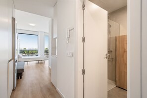 A modern hotel room with a balcony, a shower, and a view of the outdoors.