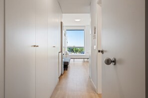 A hallway leading to a balcony with a view, white walls, and a door with a lock.
