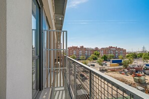 A balcony with a view of a construction site, buildings, and a clear sky.